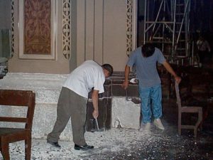 Workers in the main cathedral entrance chip away the plaster on the base of a column presumably to redo it.