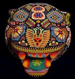 This work is entitled 'The Trance of Passage.' The wooden puma head is covered with a multitude of designs, including a peyote cactus, butterflies, a deer, a serpent, a two-headed eagle, sea turtles, a double spiral and a scorpion. According to Huichol artisan Kupíha'ute-Itzpapalotl, the wooden puma head itself symbolizes the hunting spirit of the aboriginal shamans. © Erin Cassin, 2006