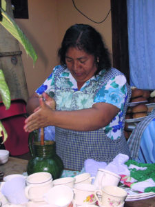 Dolores Chavez prepares hot chocolate for a fiesta. By rubbing her hands back and forth, she spins the molinillo, whipping the chocolate to frothy goodness. © Norma Hawthorne 2008