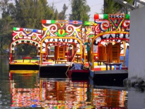 The colourful wooden boats of Xochimilco, called 'trajineras,' were once festooned with arches of fresh flowers and sweeping branches of junipers. Today, they are decorated with brightly painted flowered wooden arches, each one with a woman's name — Maria Isabel; Carmelita, Lupita. © Edythe Anstey Hanen, 2013