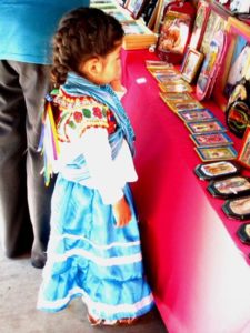 A girl chooses a Virgen de Guadalupe token as a special reminder of the day and to keep with her as a type of amulet © Tara Lowry, 2014