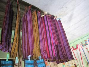 Lengths of handloomed fabric with horizontal stripes of red, black, blue and purple are sold to make skirts, called pozahuanacos, in Mixtec communities of Oaxaca, Mexico. © Geri Anderson, 2011
