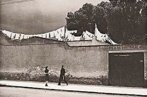 How Small The World Is (1942) A man and a woman pass each other on a sidewalk in a chance encounter. Behind them a wall beyond which hangs laundry signifying another world. The subject is not the wall, the couple, or the laundry. It's the indefinite mood that arises from the gentle collision of the three - a feeling that cannot be pinned down. For a fleeting moment, paths intersect on a city street.