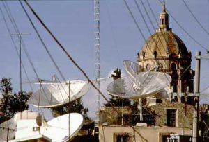 The dome of Las Monjas, "the Nuns", rises magnificently behind the clutter of today's technology, satellite dishes receiving CNN for cable subscribers.
