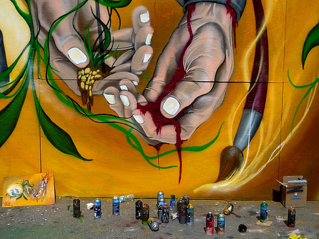 The graffiti artist's tools of the trade-spray paint cans-lie at the base of a dramatic impression by a wall artist in Mexico City. © Anthony Wright, 2009