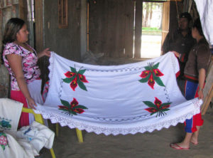 Elena Reyes Remigio, left, shows off a traditional Michoacan tablecloth she crafted. The embroidery motifs are created with punto de cruz (cross stitch) so intricate she must count the threads between each stitch. © Travis Whitehead, 2009