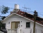 A private home is crowned by an old fashioned asbestos water tank.