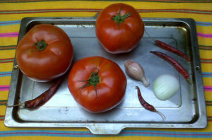 Tomatoes, chile de arbol, garlic and onion on an oven tray ready to be roasted. I let them blacken a bit for a deeper flavor. You can also char these ingredients on the stovetop in a hot, dry skillet or griddle. © Daniel Wheeler, 2009