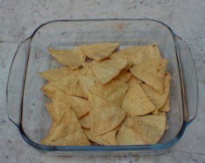 Arrange the tortilla chips, known as totopos, in a shallow baking dish. If you fry your own, cut or tear them in pieces, then let them sit uncovered overnight to toughen. This way, they don't absorb so much oil when fried. © Daniel Wheeler, 2009