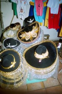 Gold-trimmed sombreros are just some of the many items found at Mercado Juárez. Notice the embroidered dresses in the background.