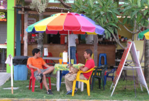 Waiting for Los Abuelos restuarant to open, its waiters befriend the dog. The restaurant in Tecolutla, Mexico, is a 1950s-style hamburger hut. © William B. Kaliher, 2010