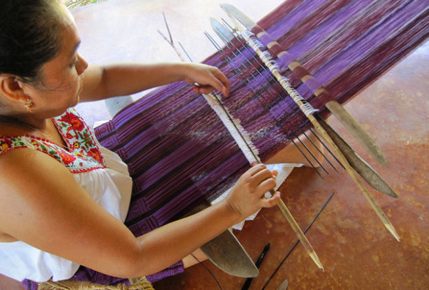 Intricate geometric motifs come to life on a warp of red, black and purple as a skilled weaver works on the backstrap loom. She is a member of the Tixinda women's cooperative in Pinotepa de Don Luis, Oaxaca. © Geri Anderson, 2011