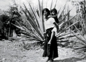 Slave mother with child and henequen plant. The Yaqui people were famed for being hard-working and strong. Between 1904 and 1909, around 15,000 of them were rounded up, forced along the tortuous route to Yucatan and enslaved. Photo from Barbarous Mexico by K. Turner © K. Turner, 1910 John Pint