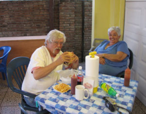 Author Bill Kaliher bites into a delicious hamburger, served by restaurateur Lois Hendriksen (right) in Tecolutla, Veracruz. © William B. Kaliher, 2010