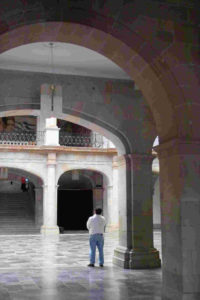 Standing at the entrance of Oaxaca's presidential palace, a man looks upward toward the murals on the second floor. © Dan Ellsworth, 2009