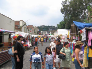 People of all ages stroll the Sunday craft market. In this scene, clothing and hats attract shoppers' attention. © Julia Taylor 2007