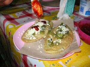 Traditional tlacoyos dressed with cheese, green nopal cactus, and salsa await a hungry diner. © Julia Taylor 2007